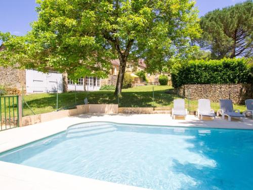 une piscine avec deux chaises et un arbre dans l'établissement Maison périgourdine avec piscine et jardin à Saint-Avit-Sénieur - FR-1-616-104, à Saint-Avit-Sénieur