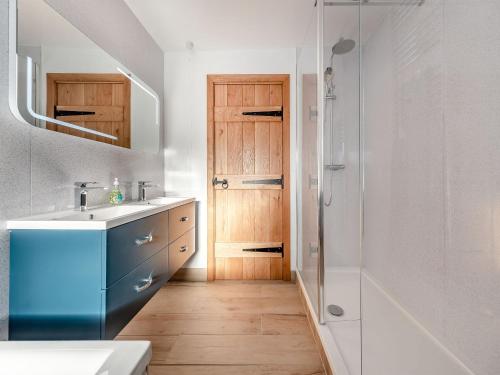 a bathroom with a sink and a shower and a door at Parlwr Godro - Uk41513 in Llanfair Clydogau