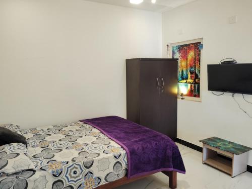 a bedroom with a bed and a dresser and a tv at Valley homes in Ooty