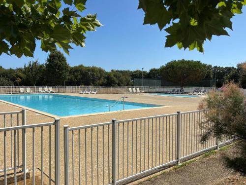 une piscine entourée d'une clôture dans l'établissement Maison de Vacances 2* avec Piscine Chauffée, Proche Plage et Commerces - FR-1-197-492, à Saint-Hilaire-de-Talmont