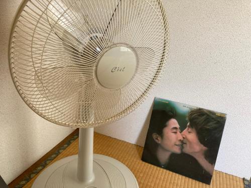 a white fan next to a picture of a couple at わくわく自然体験の宿ゲストハウス山楽 in Itoigawa