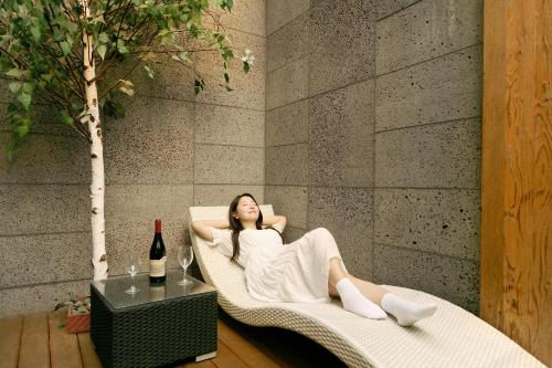a woman laying in a wicker chair next to a wall at K Boutique Hotel in Yeosu
