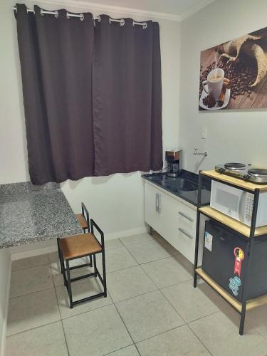 a small kitchen with a table and a microwave at Apartamento loft in Poços de Caldas