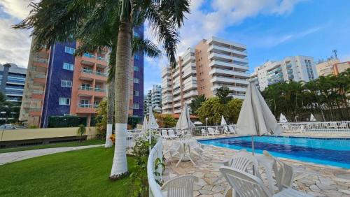 a pool with white chairs and trees and buildings at Riviera de São Lourenço Boulevard Travel inn in Bertioga