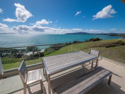 a picnic table on a balcony with a view of the ocean at Doubtless Bay Villas in Cable Bay