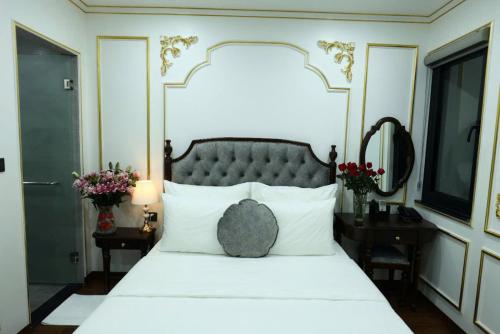 a bedroom with a white bed with a black headboard at Royal Hotel Kangnam in Hanoi