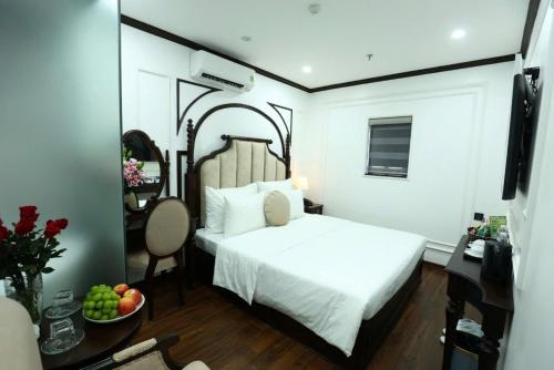 a bedroom with a bed and a table with a bowl of fruit at Royal Hotel Kangnam in Hanoi