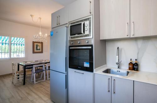 a kitchen with a refrigerator and a sink and a table at Charming Malaga Retreat, Main House plus Cozy Casita in Málaga