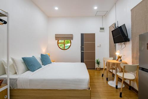 a bedroom with a bed and a table and a television at Sachi Minimal House Bangtao Beach - Near Muay Thai Gym in Ban Lum Fuang