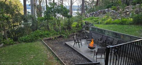 a firepit with chairs and a table with a fire burns at Dux Nutz in Smiths Lake