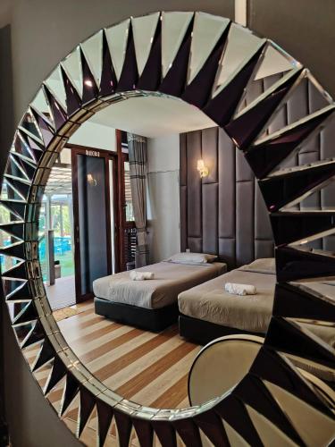 a mirror reflecting a bedroom with two beds and a table at Chan Living in Semporna