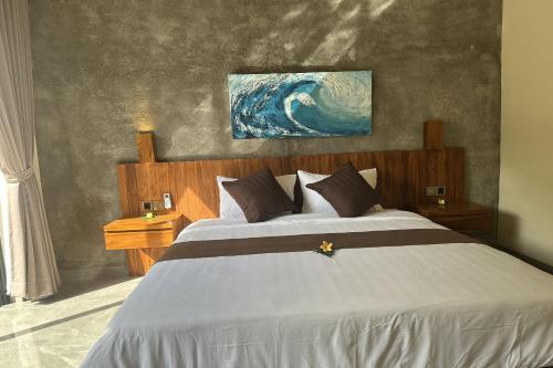 a bedroom with a large bed and a painting on the wall at Nawan Nusa Dua Bali in Nusa Dua