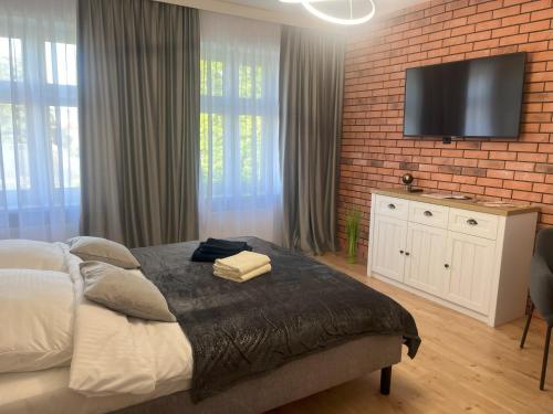 a bedroom with a bed and a tv on a brick wall at Apartament 8 in Toruń