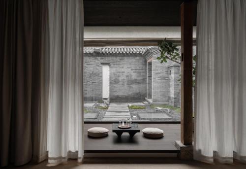 a room with a window with a table and stools at YANN壹岩古城民宿 Natural Wabi-Sabi in Datong