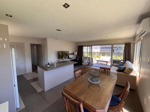 a kitchen and living room with a wooden table and a kitchen and a tablektop at Mount golf & beach retreat in Mount Maunganui