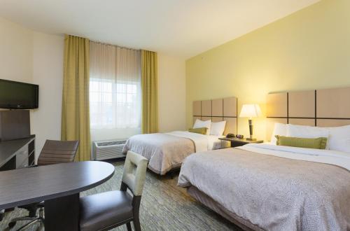 a hotel room with two beds and a table at Candlewood Suites San Marcos by IHG in San Marcos