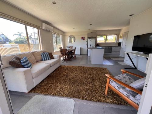 a living room with a white couch and a television at Mount golf & beach retreat in Mount Maunganui
