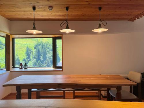 a dining room with a wooden table and a window at Fuku Chalet in Hakuba
