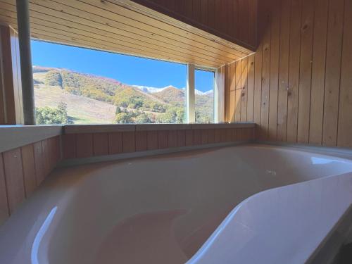 a large bath tub in a room with a window at Fuku Chalet in Hakuba