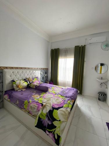 a bedroom with a large bed with a purple comforter at Kasdin Hotel Pati in Pati