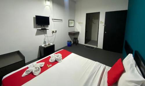 a bedroom with a red and white bed with shoes on it at Captain Hotel Cafe & Bistro in Sitiawan