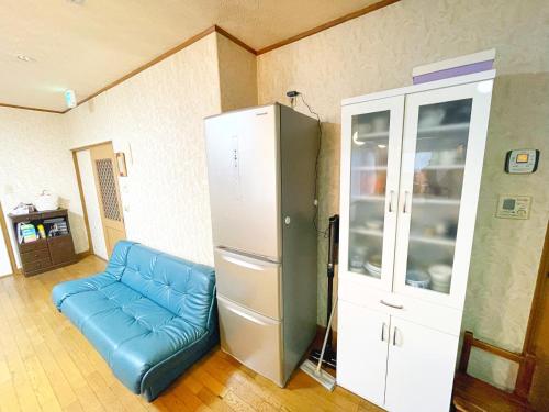 a living room with a blue couch and a cabinet at 青森駅近7名まで同一料金ファミリー向け小学生添い寝無料コンドフルカワ青森 in Aomori
