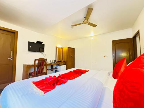 a bedroom with a white bed with red pillows at City Palace Residency Nilambur in Wandūr