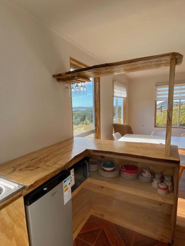a kitchen with a counter with a refrigerator and a bed at Cabaña puesta de sol in Ancud