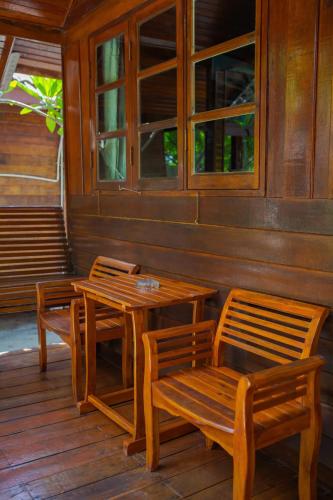 a wooden porch with two tables and two chairs at Chareena Beachside in Ko Lipe