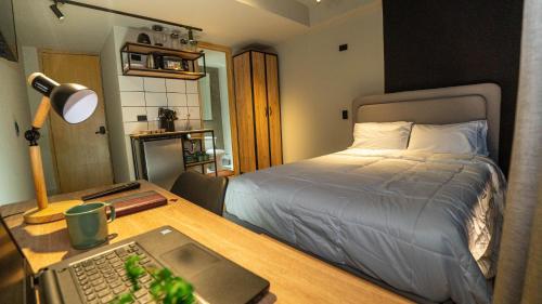 a bedroom with a bed and a desk with a laptop at NUIT Bogota in Bogotá