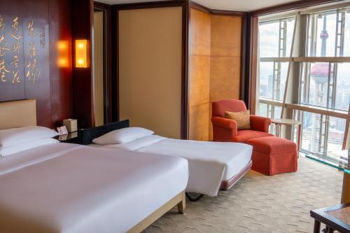 a hotel room with two beds and a chair at Grand Hyatt Shanghai in Shanghai