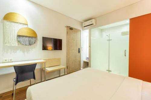 a bedroom with a bed and a desk and a television at Cove Renata in Seminyak