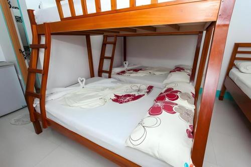 two bunk beds with white sheets and flowers on them at Palm Grove Saud Holiday Complex Hotel in Laoag