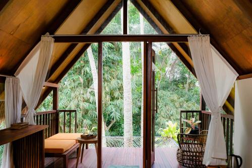 an open glass door to a porch with trees at Ubud Jungle Stay by WAHM Hotel Management in Ubud