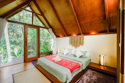 a bedroom with a large bed in a room with windows at Ubud Jungle Stay by WAHM Hotel Management in Ubud