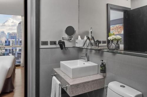 a bathroom with a sink and a toilet and a window at F1 Hotel Manila in Manila