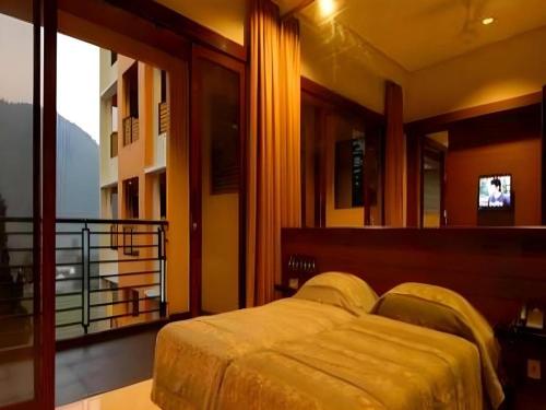 a bedroom with a bed and a balcony with a television at Hotel Bintang Tawangmangu in Tawangmangu