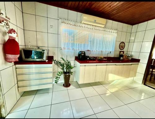 a kitchen with white tiled walls and a window at Residencial Celedone in Boa Vista