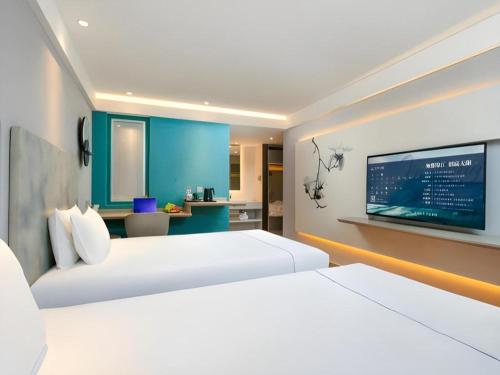 a hotel room with two beds and a flat screen tv at Magnotel Ningbo Tianyi Plaza Railway Station in Ningbo