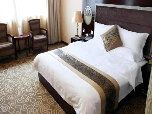 a hotel room with a large bed and a chair at Juntong Hotel in Bao'an