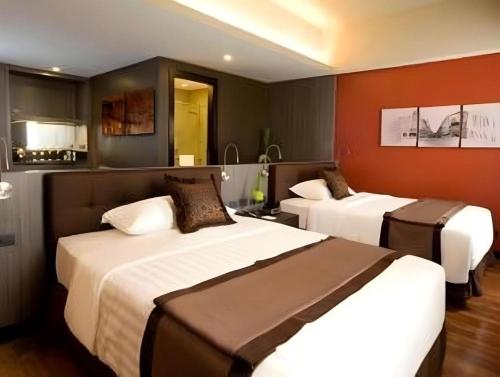 two beds in a hotel room with red walls at F1 Hotel Manila in Manila