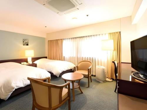 a hotel room with two beds and a television at Oita Century Hotel in Oita
