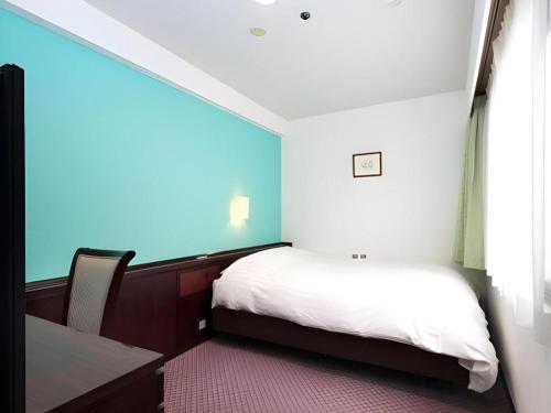 a small bedroom with a bed and a window at Oita Century Hotel in Oita