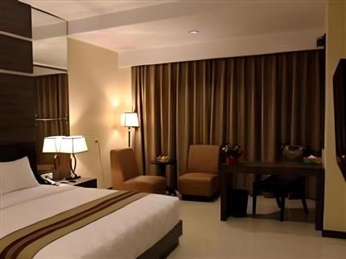 a hotel room with a bed and a desk at Mega Permata Hotel in Padangsidimpuan