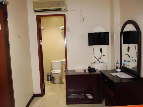 a bathroom with a toilet and a sink and a mirror at Hotel Dynasty in Tarakan