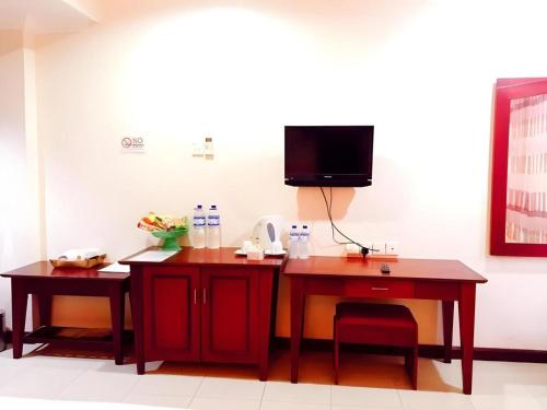 a room with two tables and a tv on a wall at Hotel Dynasty in Tarakan