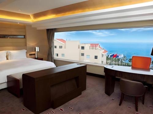 a hotel room with a bed and a large window at Grand Metropark Hotel Qingdao in Qingdao