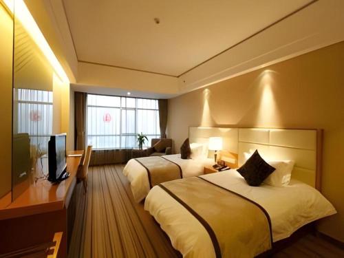 a hotel room with two beds and a television at The Prosperous City Hotel Weifang in Weifang