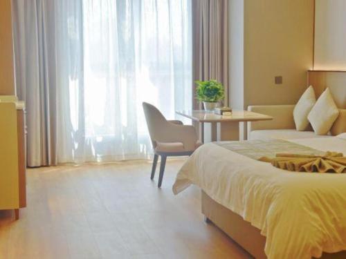 a bedroom with a bed and a table with a chair at Chengdu Antai Century Hotel in Chengdu