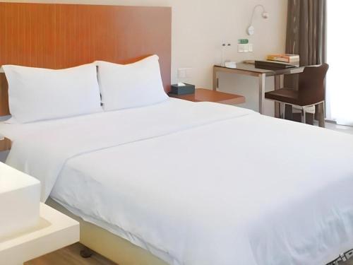 a large white bed in a room with a desk at Shanshui Trends Hotel-Bantian Dong Branch in Shenzhen